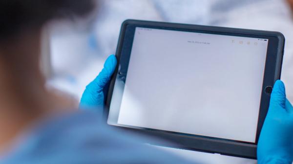 A healthcare professional holds a tablet
